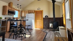 A kitchen with wooden cabinets, a black stove, a white refrigerator, and a ceiling fan. - The Bunk House (Cody)