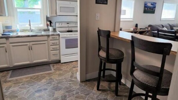 A kitchen with white cabinets, a stone floor, and two bar stools. - Easy Living ~ Easy Playing, just a 5 minute walk from down town Cody. (Cody)