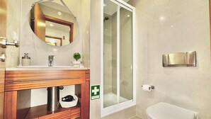A modern bathroom with a wooden vanity, a glass shower enclosure, and a white toilet.