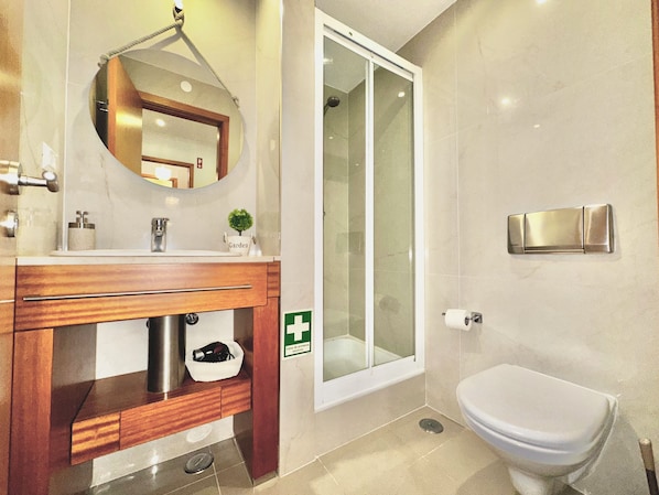 A modern bathroom with a wooden vanity, a glass shower enclosure, and a white toilet.