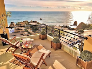 A balcony with a table, chairs, and a view of the ocean.