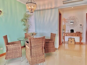 A dining area with a round table and wicker chairs, a hanging chandelier, and a wall-mounted decorative piece. - Seaview Luxury Apartment A/c Wi-Fi garage (Portimão)