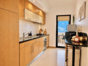 A modern kitchen with wooden cabinets, stainless steel appliances, and a view to the outside.