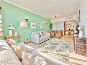 Un salon avec un canapé, un coin repas avec une table et des chaises, et une cuisine avec un comptoir et des placards.