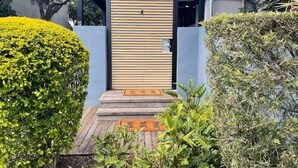 Ingresso di un edificio moderno con una porta in legno, un piccolo portico e un giardino curato.