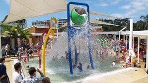 A water play area with multiple water jets and a large green ball structure.