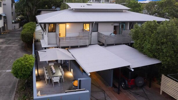 A two-story house with a covered patio, a garage, and a small garden area.
