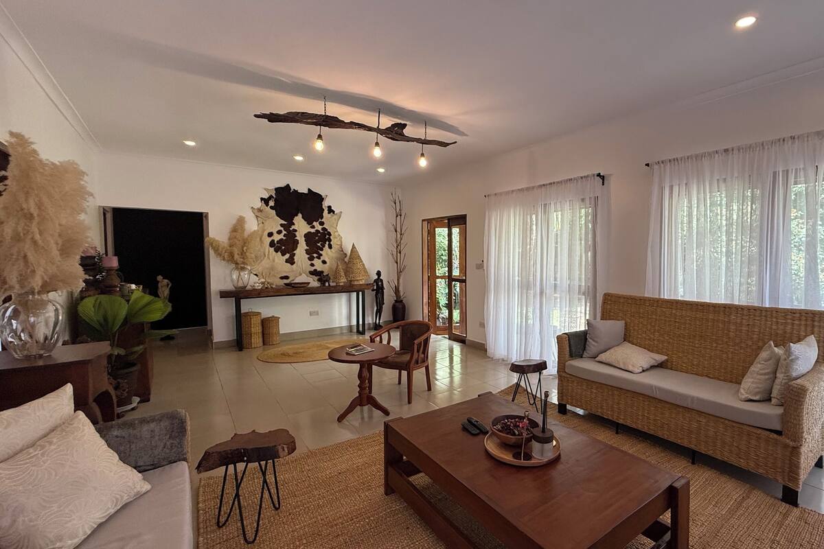 A spacious living room with a sofa, coffee table, and a large decorative piece on the wall.