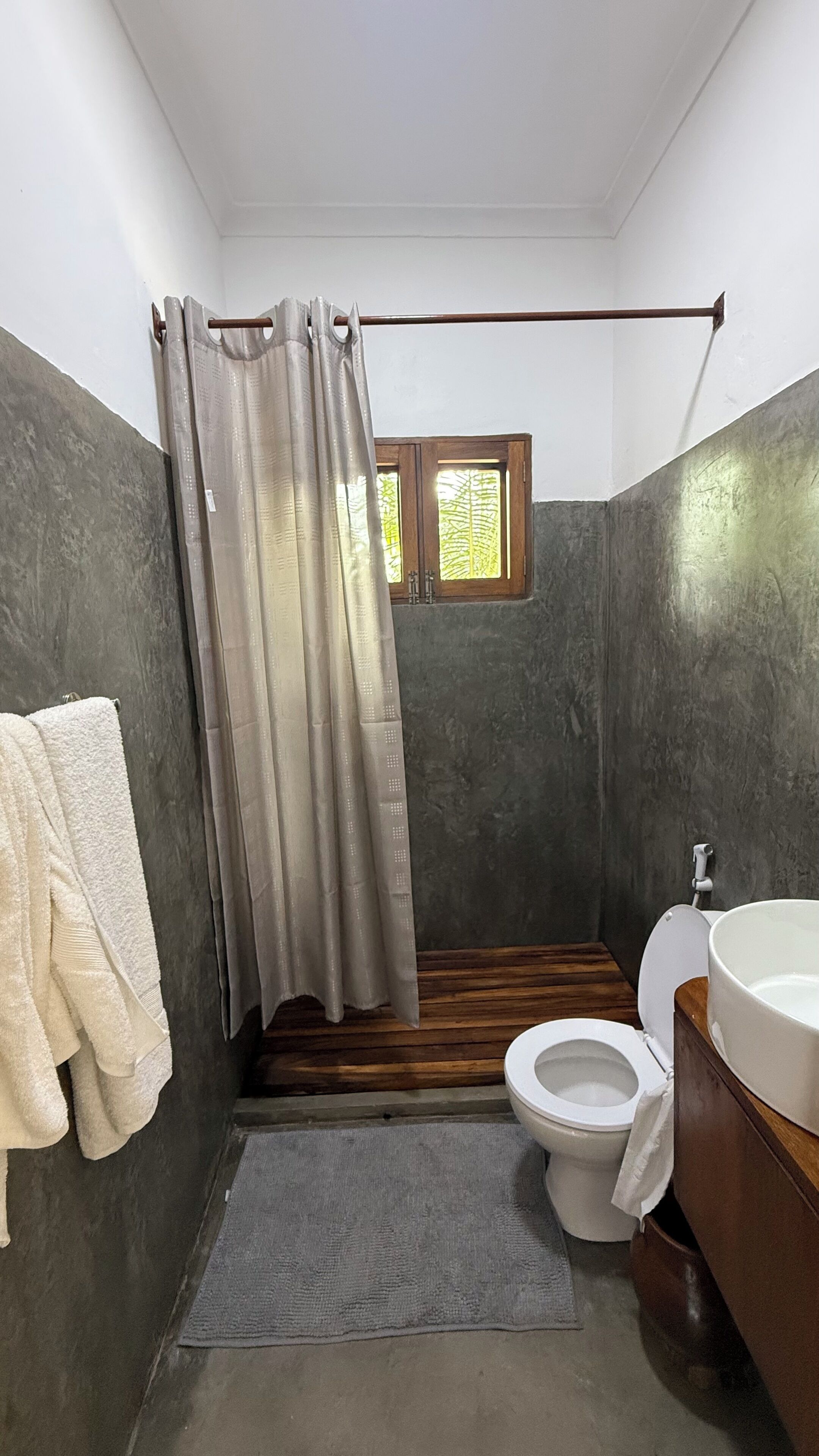 Un baño con cortina de ducha, inodoro y lavamanos.