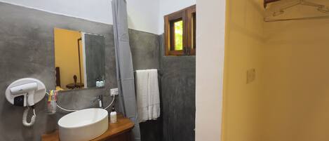 A bathroom with a white sink, a mirror, a shower, and a towel hanging on the wall.