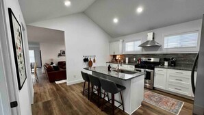 Une cuisine moderne dotée d’un îlot central, de meubles blancs et d’un plancher en bois.