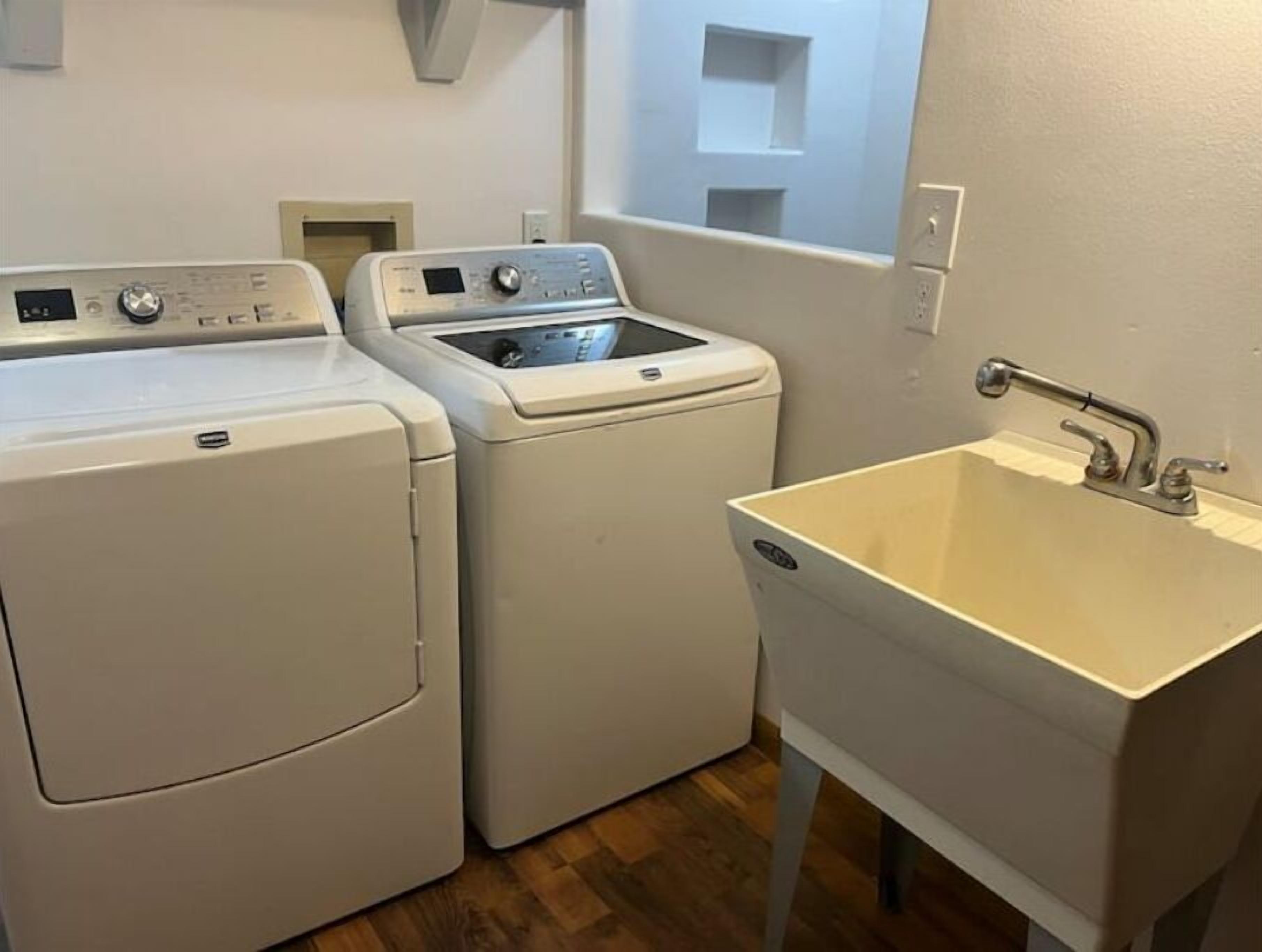 A laundry area with two front-loading washing machines and a sink.
