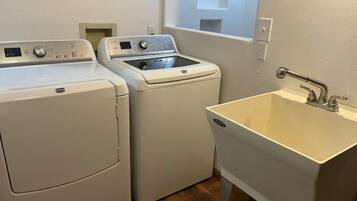 A laundry area with two front-loading washing machines and a sink.