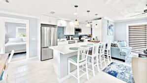 Une cuisine moderne avec des armoires blanches, des appareils en acier inoxydable et des luminaires suspendus.