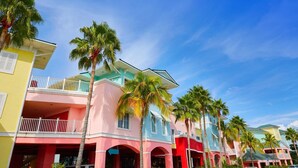 Un bâtiment coloré à plusieurs étages, doté de balcons et bordé de palmiers.