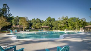 Ein Swimmingpool mit Liegestühlen und Sonnenschirmen, umgeben von Bäumen.