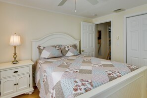 A bedroom with a bed, nightstand, lamp, and a door to another room. - Cozy Westbrook Vacation Rental - Walk to Beach! (Westbrook)