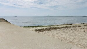 A beach with a concrete walkway, sandy shore, and calm sea. - Cozy Westbrook Vacation Rental - Walk to Beach! (Westbrook)