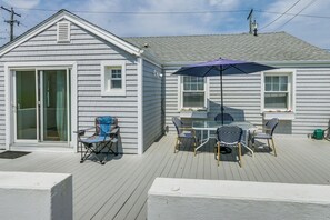 A covered patio with a table and chairs, a folding chair, and a sliding glass door. - Cozy Westbrook Vacation Rental - Walk to Beach! (Westbrook)