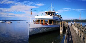 Een veerboot afgemeerd aan een steiger, met een helder uitzicht op het water en andere boten op de achtergrond.