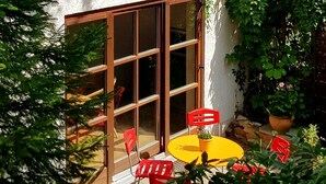 Een terras met een tafel, stoelen, een potplant en een stenen muur.