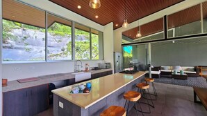 Eine moderne Küche mit einer großen Kochinsel, Barhocker und einer Sitzecke inklusive Sofa und Couchtisch.