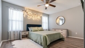 Ein Schlafzimmer mit Bett, Nachttischen, einem Schminktisch und einem Deckenventilator sowie einem großen Spiegel.