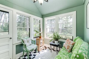 Experience a classic, inviting atmosphere in this room with a checkered floor and large windows offering views of the surrounding greenery.