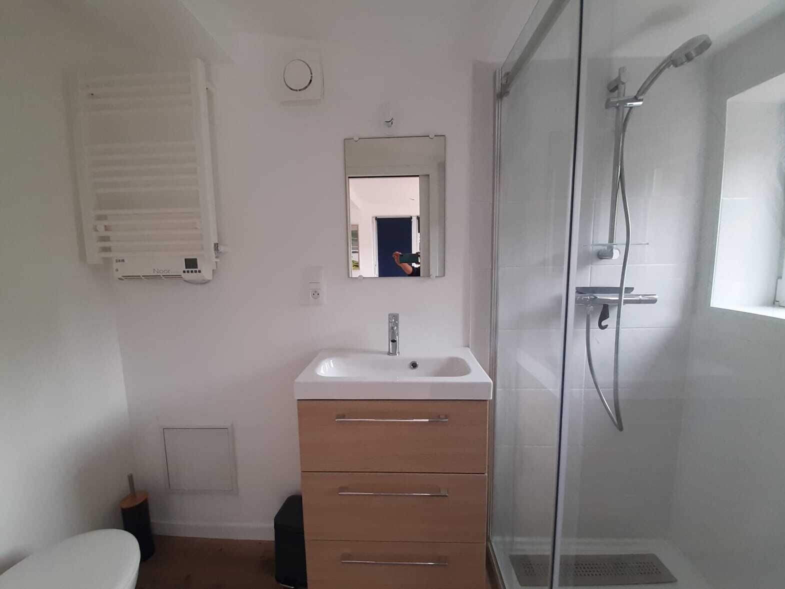 Kylpyhuone, jossa on valkoinen pesuallas, peili, suihku ja wc.