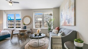 Un salon moderne avec un canapé gris, une table basse ronde et un coin repas comprenant des chaises et une petite table.