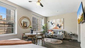 Une chambre d’hôtel moderne avec un grand lit, un coin repas doté d’une table ronde, un canapé et un téléviseur fixé au mur.