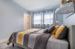 Cozy retreat with a bed, desk lamp, and floral window treatment.