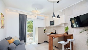 A modern kitchen with a wooden island, a built-in TV, and a dining area with bar stools. - Hedera A41 (Dubrovnik)
