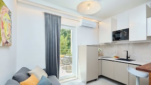 A modern kitchen with a built-in microwave, a sink, and a dining area with a bar stool. - Hedera A41 (Dubrovnik)