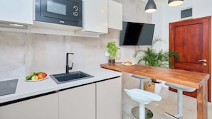 A modern kitchen with a built-in microwave, a sink, and a wooden bar counter with bar stools. - Hedera A41 (Dubrovnik)