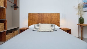 A neatly made bed with a wooden headboard, two bedside tables, and a small wooden stool. - Hedera A41 (Dubrovnik)