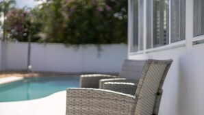 Ein Poolbereich mit Korbstühlen und freiem Blick auf den Pool.