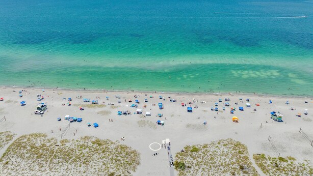 A beach with clear turquoise water, sandy shore, and several beach umbrellas. - Venice Beach-Coco Palms 103. One block to Venice Beach.  (Venice)