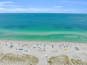 Una playa con agua turquesa cristalina, orilla arenosa y varias sombrillas.