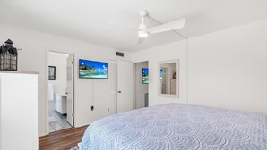 A bedroom with a bed, a ceiling fan, a painting, and a door leading to a bathroom. - Venice Beach-Coco Palms 103. One block to Venice Beach.  (Venice)