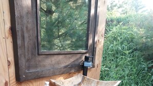 Une cabane en bois rustique, dotée d’un évier intégré, d’une fenêtre et d’une serviette suspendue à un crochet.