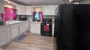 Una cocina con armarios blancos, una estufa negra y un refrigerador negro.