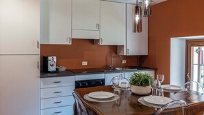 A modern kitchen with white cabinets, a wooden dining table set with plates and glasses, and a potted plant on the counter. - CASA CARMEN ( Sferisterio) near Parking (Macerata)