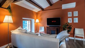 A bedroom with a bed, bedside lamps, a TV, a plant, and artwork on the wall. - CASA CARMEN ( Sferisterio) near Parking (Macerata)
