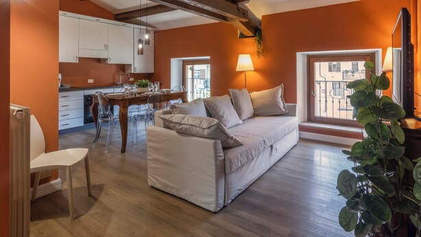 A modern living space with a sofa, dining table, and kitchen area. - CASA CARMEN ( Sferisterio) near Parking (Macerata)