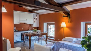 A room with a bed, a dining table with chairs, a kitchen area, and a window with a view. - CASA CARMEN ( Sferisterio) near Parking (Macerata)