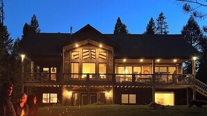 Une grande maison en bois à plusieurs étages, avec un foyer installé en premier plan.