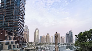 A high-rise building with a marina and boats in the foreground, and a city skyline in the background. - OSKENA Homes-Damac Heights Two Bedroom (Dubai)