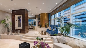 A spacious lobby with a modern design, featuring a large seating area, a reception desk, and large windows offering views of the outside. - OSKENA Homes-Damac Heights Two Bedroom (Dubai)