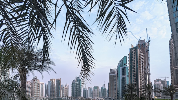 A pool area with a view of a city skyline, palm trees, and high-rise buildings. - OSKENA Homes-Damac Heights Two Bedroom (Dubai)